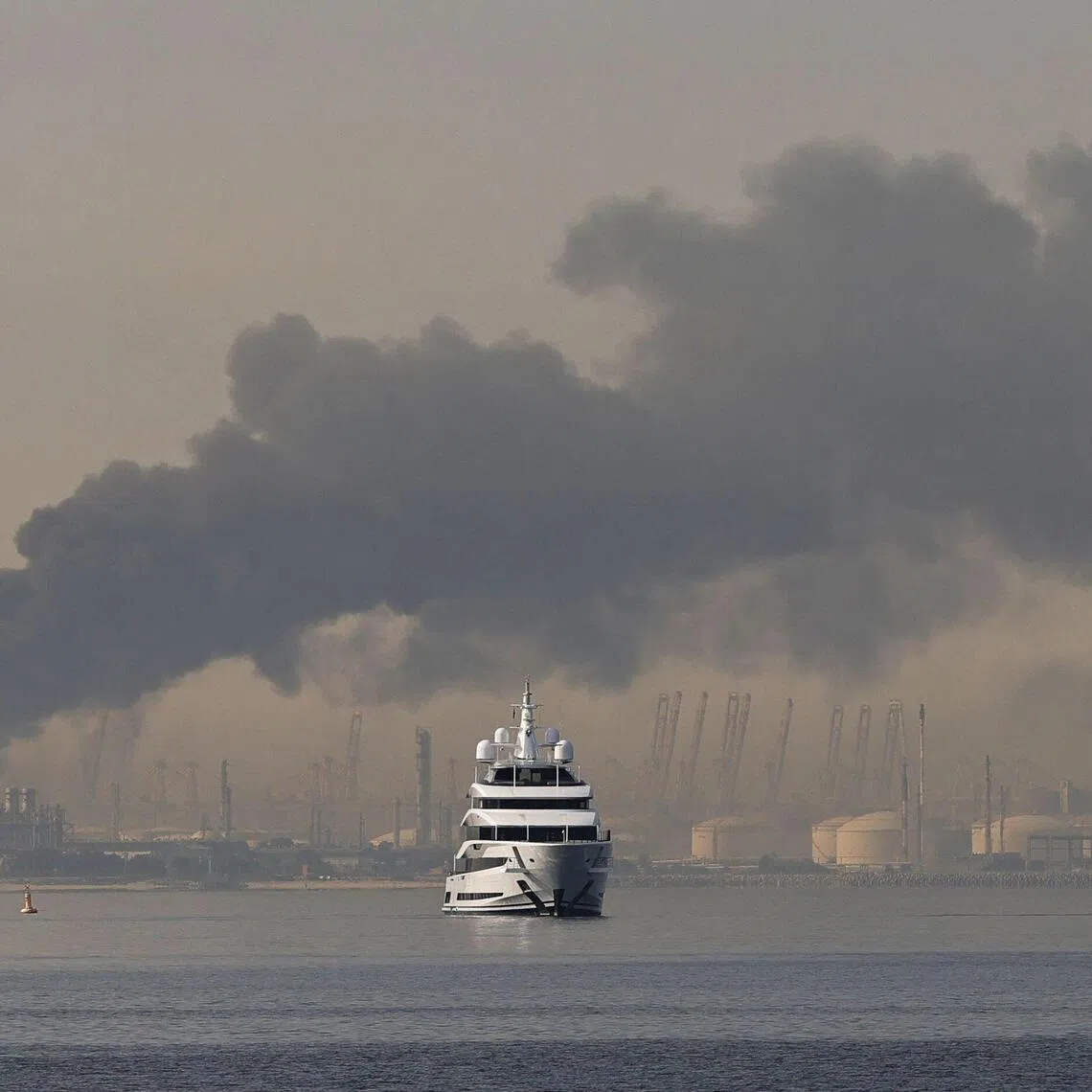 A yacht sails past a plume of smoke rising from the port of Jebel Ali following a reported Iranian strike in Dubai on March 1.