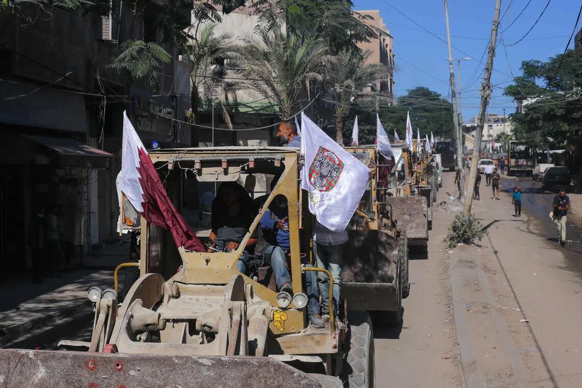 Bulldozers deployed by the Gaza Municipality drive past Palestinians on the way to clear building rubble from main axes and streets in Gaza City on Oct 14.