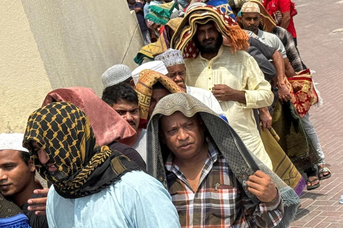 People cover their heads with prayer rugs for shade, following Friday prayers, during the summer heat in Dubai, United Arab Emirates, August 1, 2025. REUTERS/Amr Alfiky