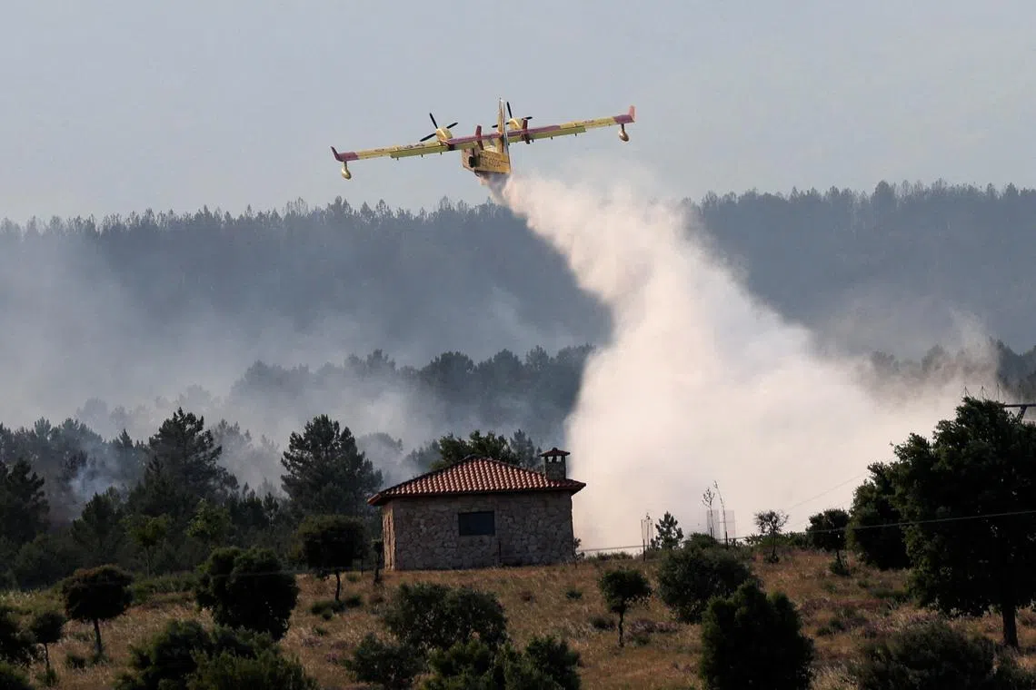 A firefighting plane dumps water, as a wildfire burns, in Hernan-Perez, Estremadura, Spain.