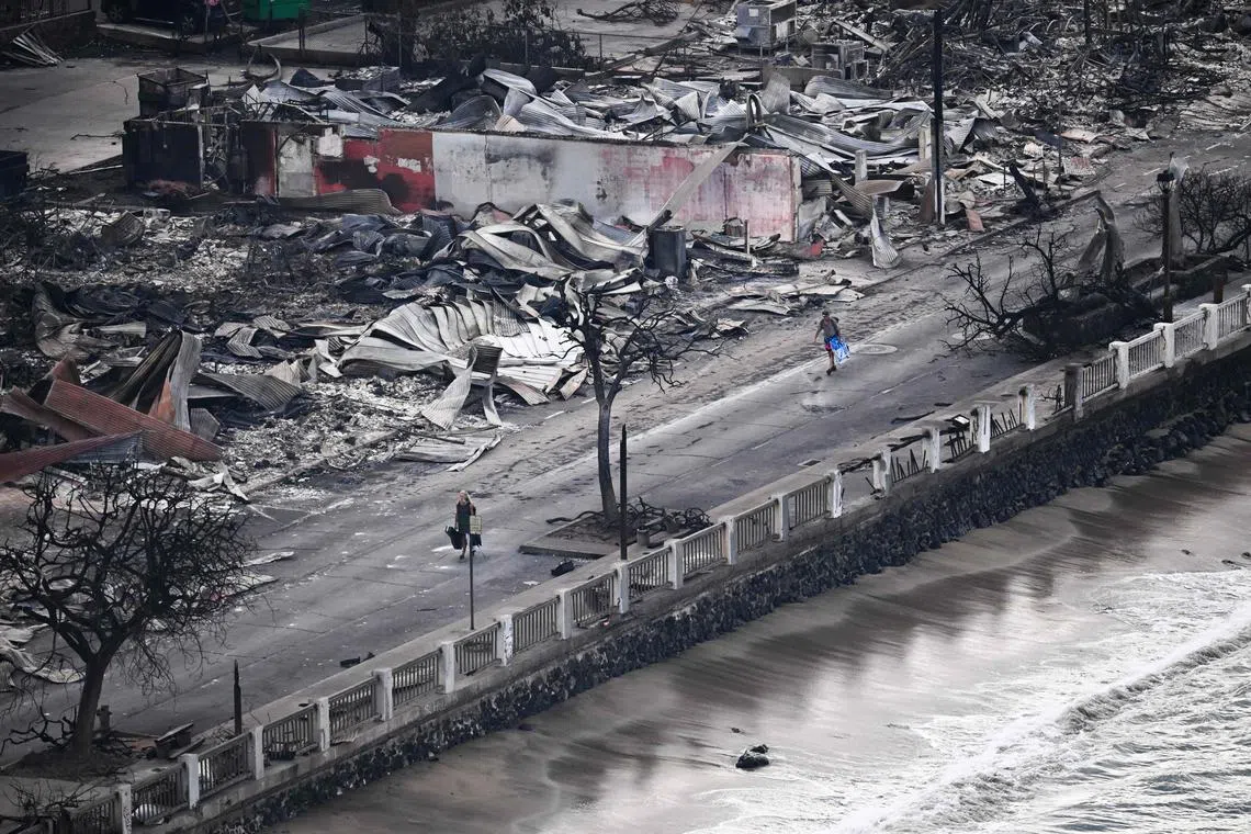 TOPSHOT - An aerial image taken on August 10, 2023 shows a person walking down Front Street past destroyed buildings burned to the ground in Lahaina in the aftermath of wildfires in western Maui, Hawaii. At least 36 people have died after a fast-moving wildfire turned Lahaina to ashes, officials said August 9, 2023 as visitors asked to leave the island of Maui found themselves stranded at the airport. The fires began burning early August 8, scorching thousands of acres and putting homes, businesses and 35,000 lives at risk on Maui, the Hawaii Emergency Management Agency said in a statement. (Photo by Patrick T. Fallon / AFP)