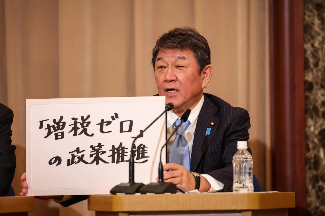 FILE PHOTO: TOKYO, JAPAN - SEPTEMBER 14:  Liberal Democratic Party secretary general Toshimitsu Motegi, a candidate for Japan’s ruling Liberal Democratic Party’s (LDP) presidential election,  holds up a sign during a debate at the Nixon Kisha Club in Tokyo, Japan. Takashi Aoyama/Pool via REUTERS/File Photo