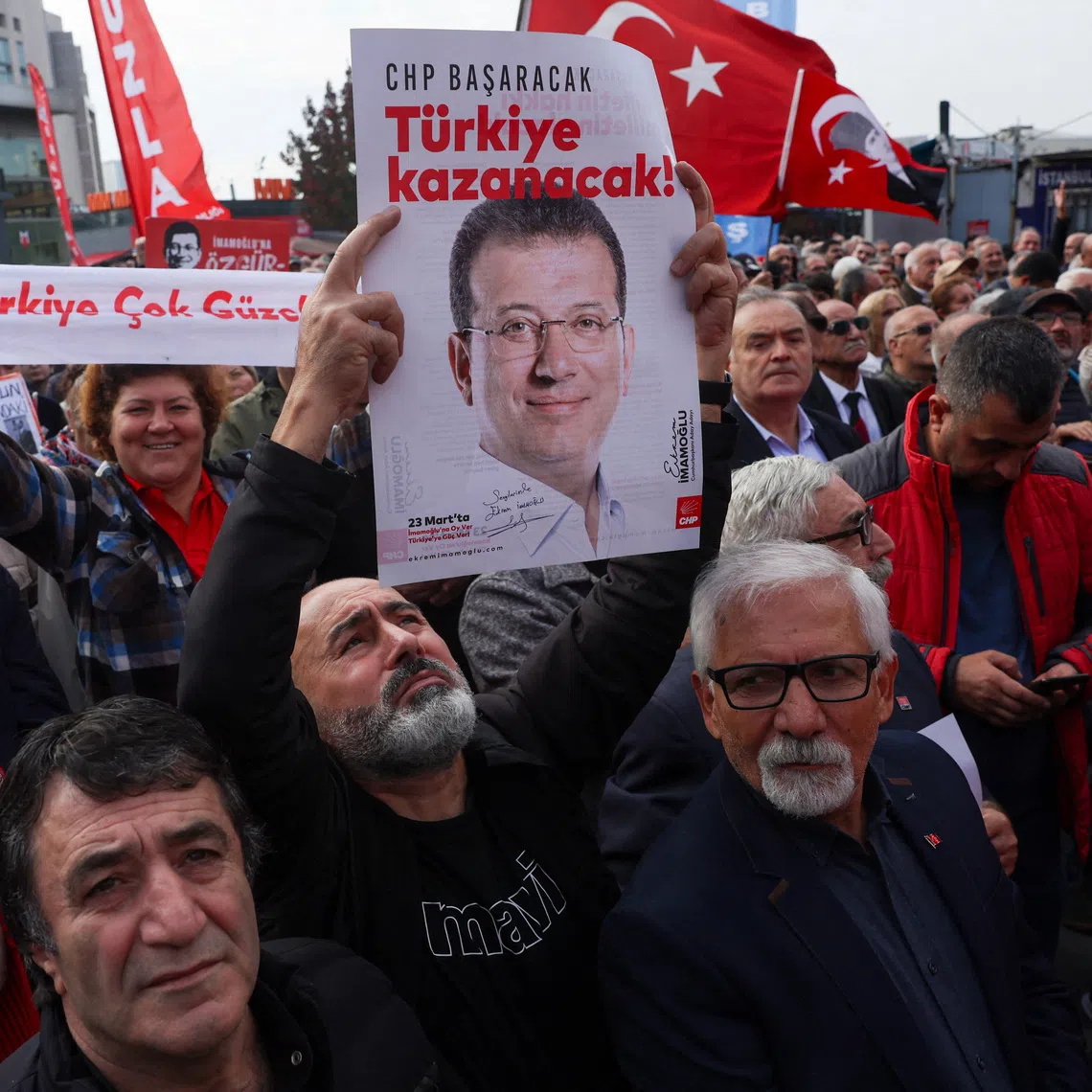 A supporter of the main opposition Republican People's Party (CHP) holds a poster featuring a picture of jailed Istanbul Mayor Ekrem Imamoglu and a slogan \"CHP will succeed, Turkey will win\" reads on it, during a protest near the Justice Palace, known as Caglayan Courthouse, as Imamoglu testifies in a new investigation over alleged espionage, in Istanbul, Turkey, October 26, 2025. REUTERS/Dilara Senkaya
