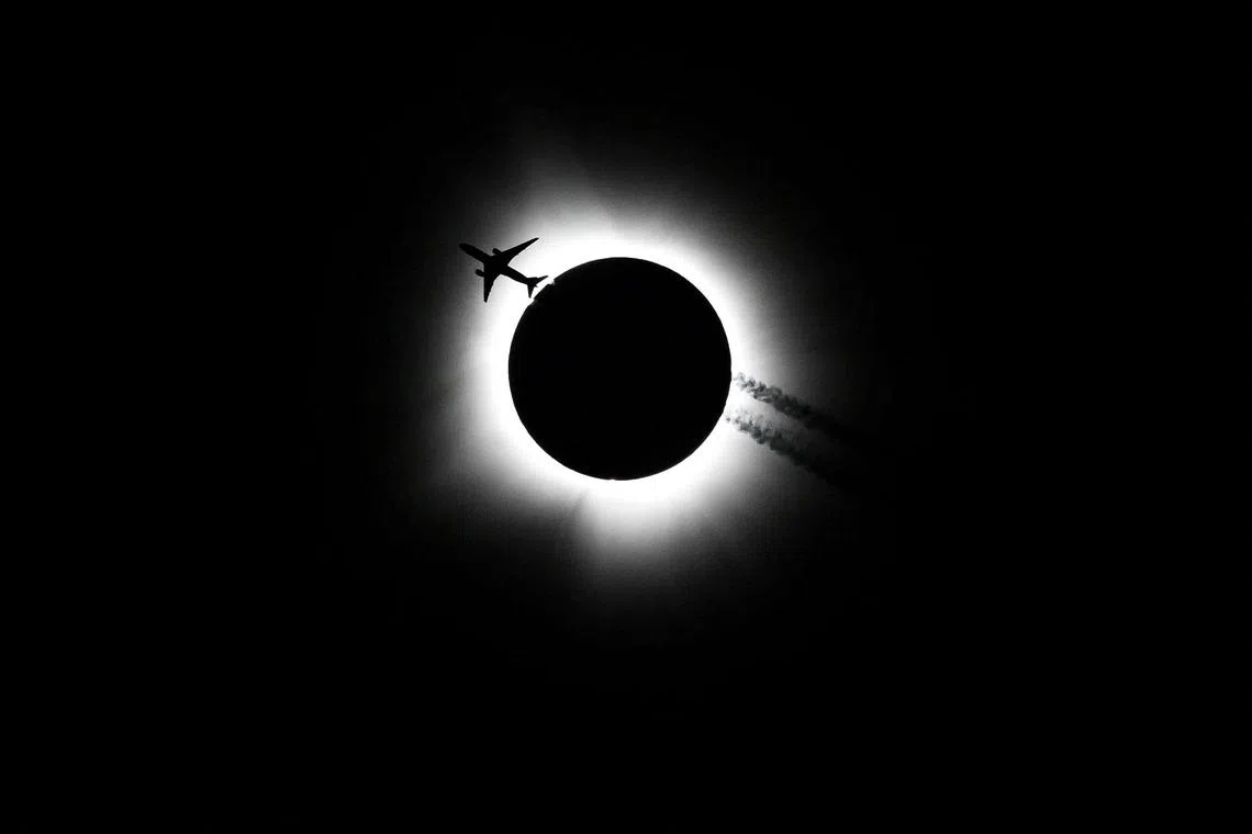 An airplane passing near the total solar eclipse during the Hoosier Cosmic Celebration at Memorial Stadium in Bloomington, Indiana, on April 8, 2024. 