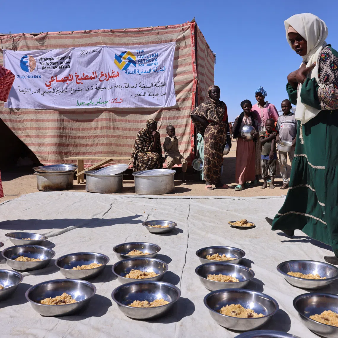 Najwa Isa Adam (L), 32, a Sudanese refugee from al-Fashir, prepares bowls of pasta and meat for orphaned children and newly arriving refugee families using donated money at the Tine transit camp in eastern Chad, November 22, 2025. Najuwa says she was held captive at gunpoint by four Rapid Support Forces (RSF) fighters who repeatedly raped her amid the conflict with the Sudanese army. REUTERS/Amr Abdallah Dalsh