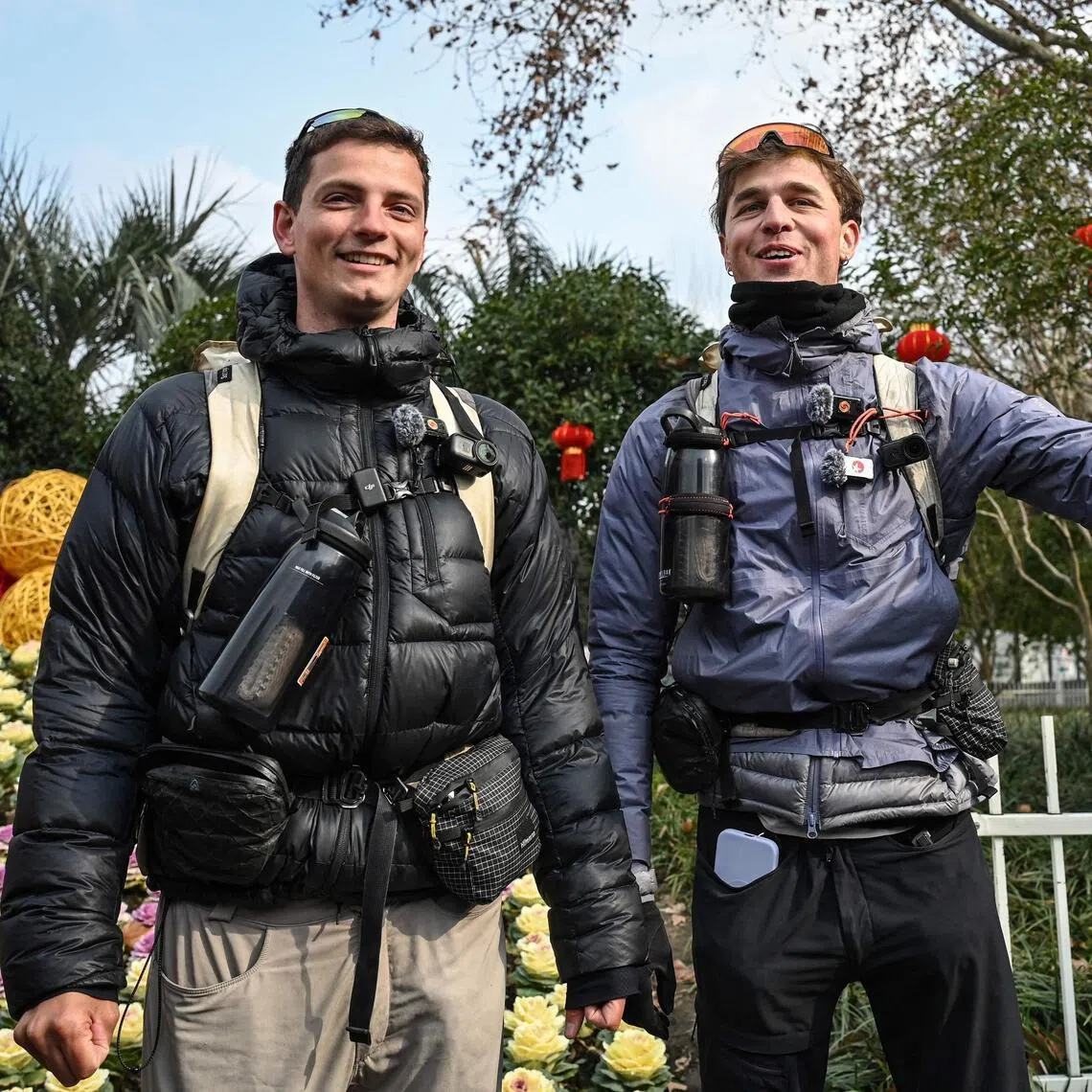 TOPSHOT - France's Loic Voisot (R) and Benjamin Humblot speak to media and local residents at Changfeng Park, before completing the final leg of their walk from France to China, in Shanghai on February 7, 2026. Two French adventurers reached the end of an epic walk from France to Shanghai on February 7, after nearly a year and a half crossing 16 countries almost entirely on foot. (Photo by Jade GAO / AFP)