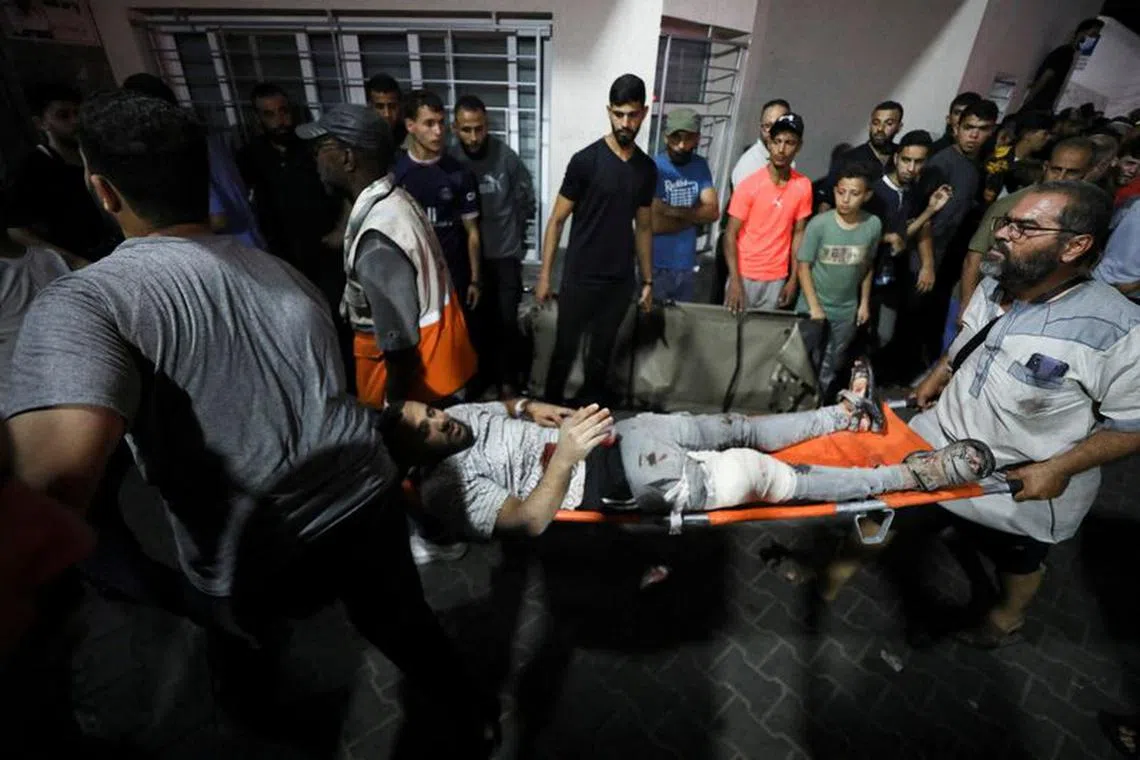 An injured person is assisted at Shifa Hospital after an Israeli air strike hit the nearby Al-Ahli Hospital, according to Gaza Health Ministry in Gaza City, Gaza Strip, October 17, 2023. REUTERS/Mohammed Al-Masri