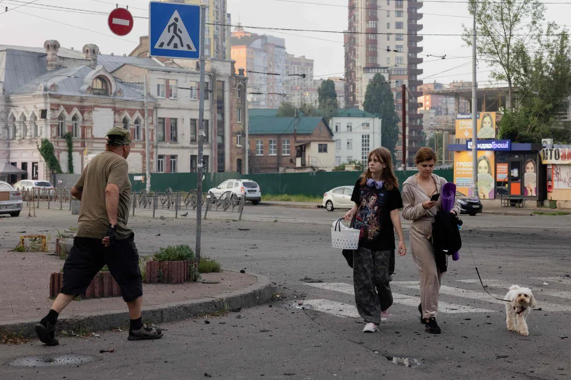 People leave a shelter with their belongings near a damaged shopping centre after a night of Russian strikes in Kyiv, on July 10.