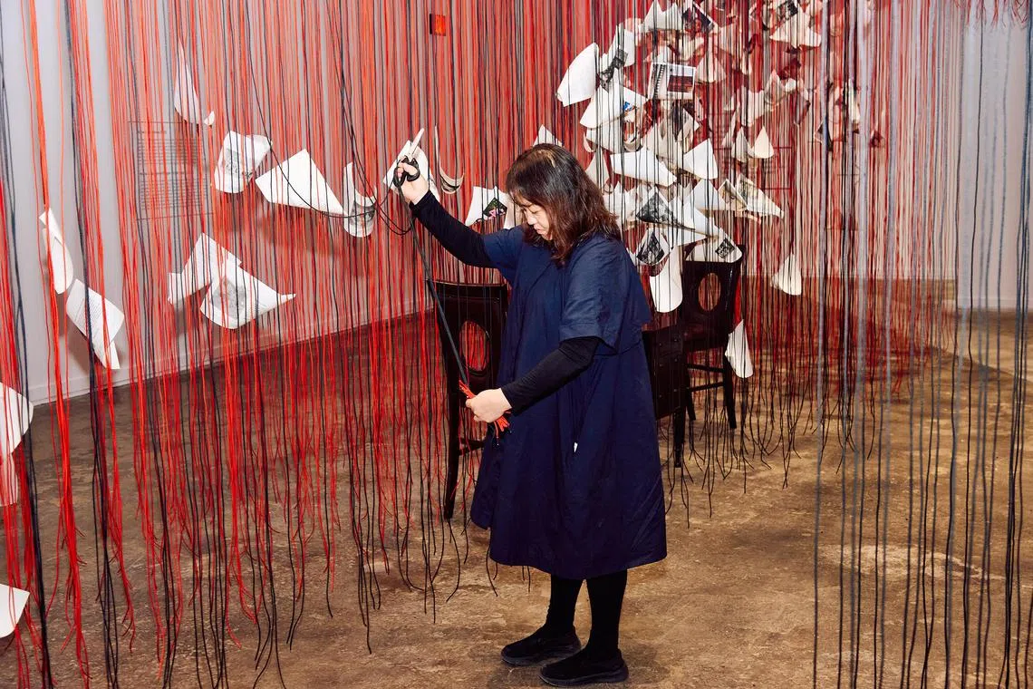O artista Chiharu Shiota inspeciona uma instalação na ICA Watershed, um enorme espaço de exposição em um estaleiro ativo em Boston em 16 de maio de 2025. O artista de Berlim evocou uma infinidade de histórias de imigrantes em 