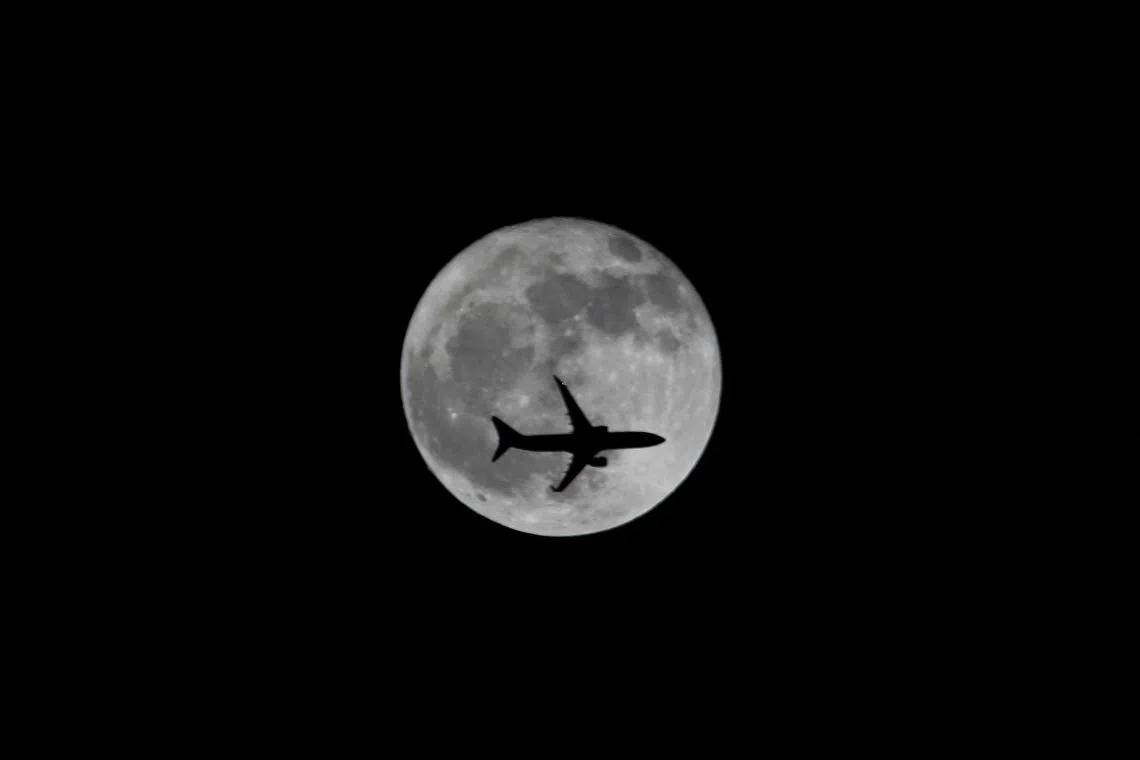 FILE PHOTO: A passenger plane passes the moon as it comes into land at the international airport in Chennai, India, September 25, 2018. REUTERS/P. Ravikumar/File Photo
