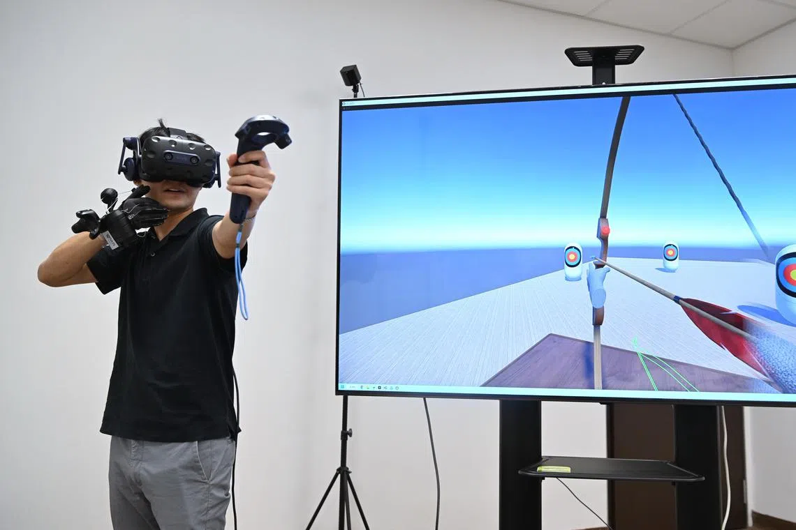 Photo of Straits Times journalist Osmond Chia testing a virtual reality archery simulation with the HaptGlove, developed by researchers from the National University of Singapore, on Jan 13. 