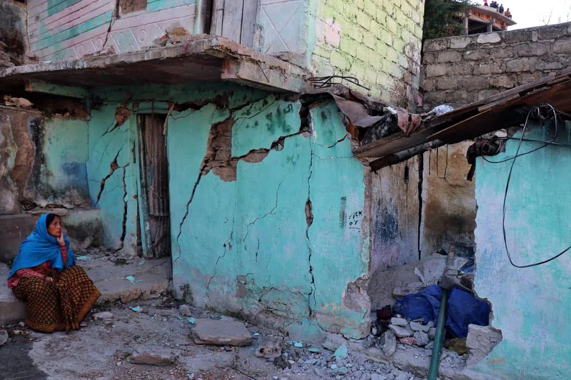 A resident sits next to the cracked wall of her house in the town of Joshimath, in Chamoli district of India's Uttarakhand state, on Jan 8, 2023. 