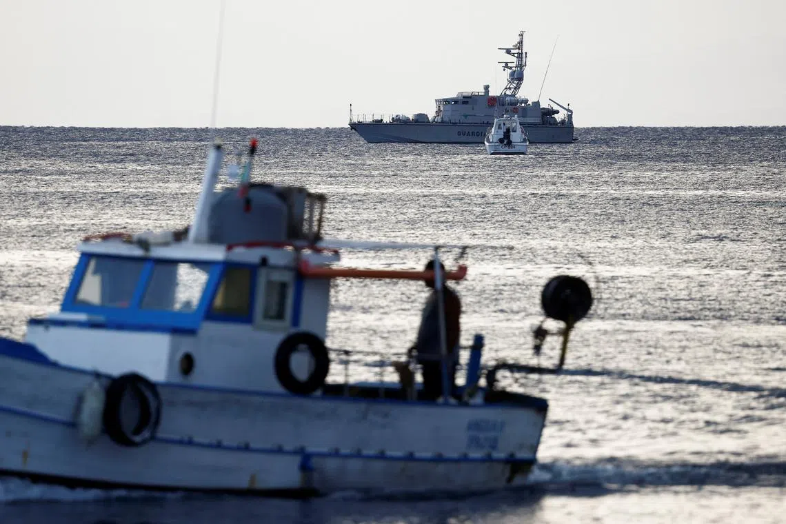 A fishing boat sails past a finance police vessel and a coast guard vessel operating in the sea to search for the missing, including British entrepreneur Mike Lynch, after a luxury yacht sank off the coast of Porticello, near the Sicilian city of Palermo, Italy, August 20, 2024. REUTERS/Guglielmo Mangiapane