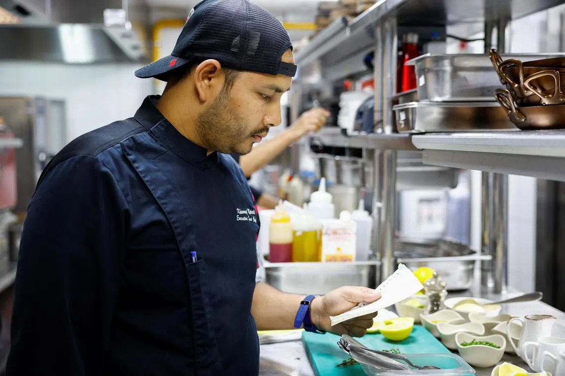 Chef Khimraj Nepali looks at the recipe taken from “Aiman”, the AI Chef, at the Trove Restaurant in Dubai.