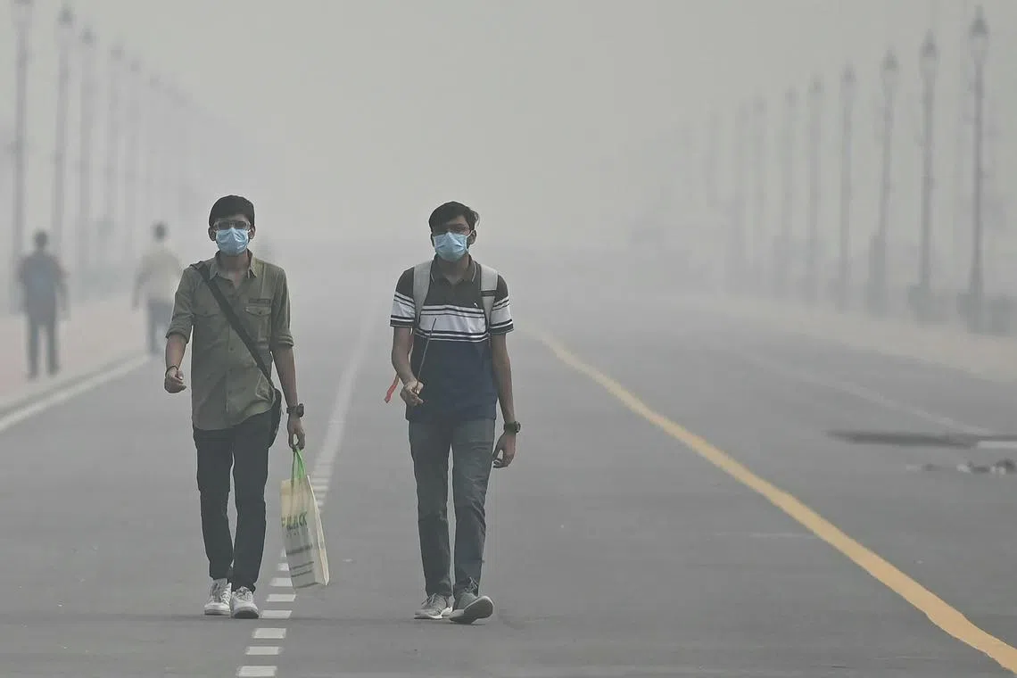 People wearing face masks walking along the Kartavya Path amid heavy smoggy conditions in New Delhi on Nov 5, 2023. 