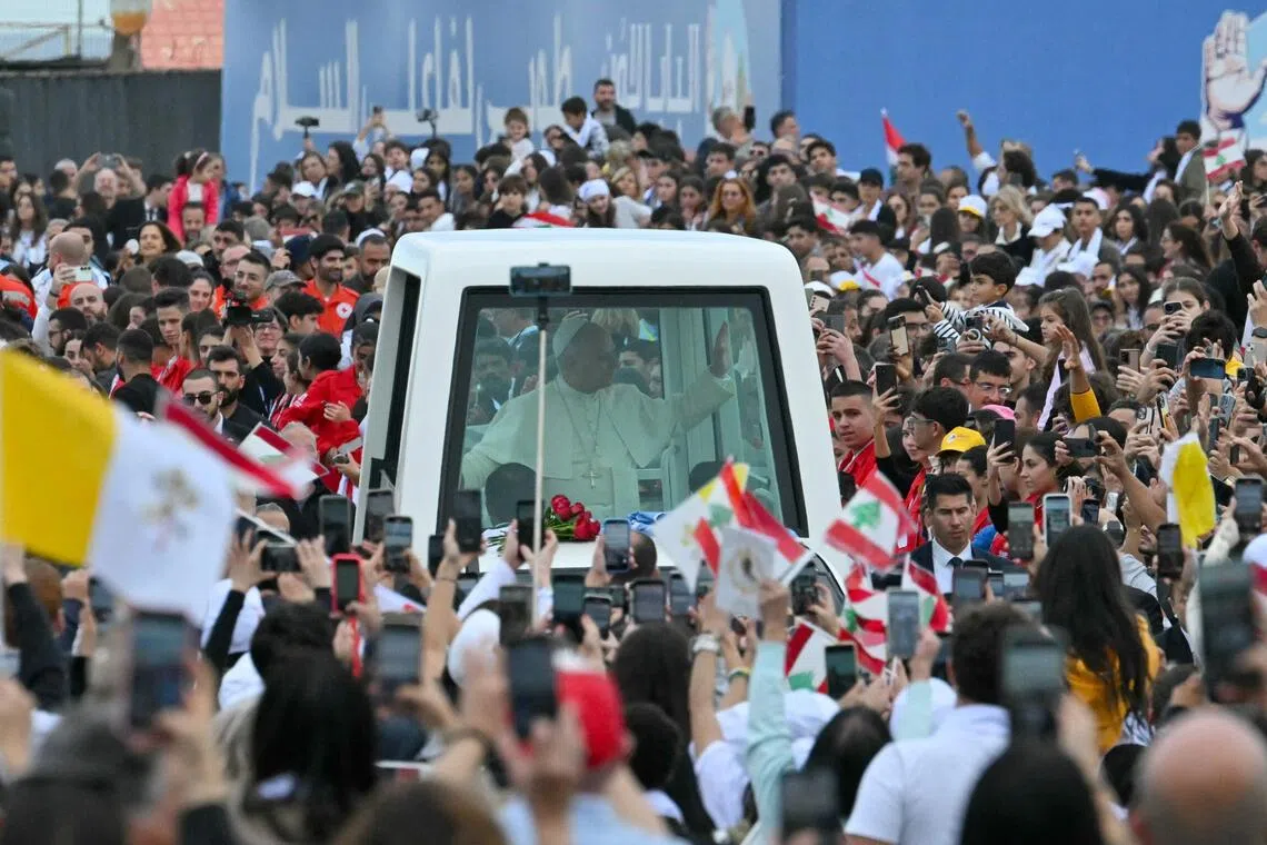 Pope Leo XIV waves to the crowd from inside his “popemobile” as he arrives for a mass at Beirut's waterfront on Dec 2, 2025.
