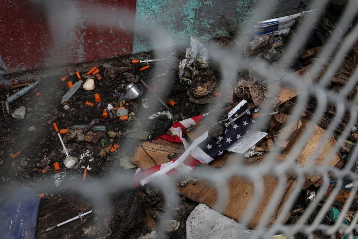 Debris left by drug users lies next to a tattered  U.S. flag, in the Bronx borough of New York City, U.S., June 15, 2023.  REUTERS/Shannon Stapleton