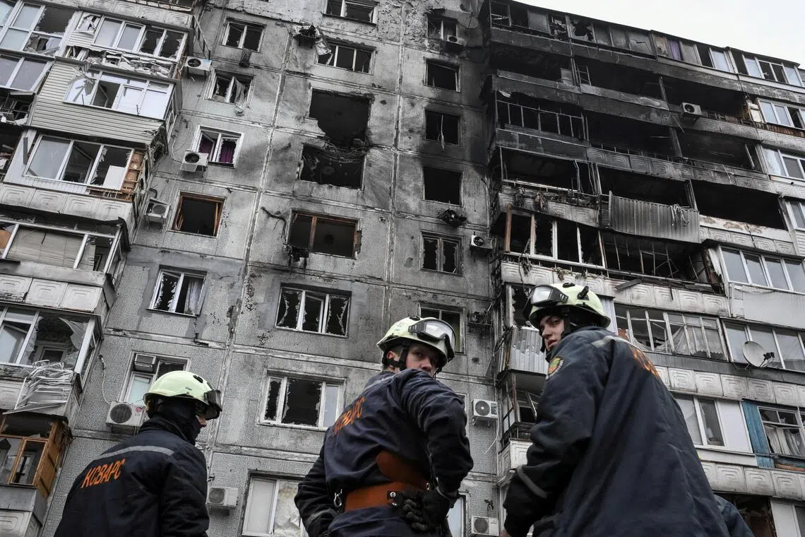 Rescuers standing near an apartment building hit by a Russian drone strike, in the Ukrainian city of Zaporizhzhia, on Dec 16.