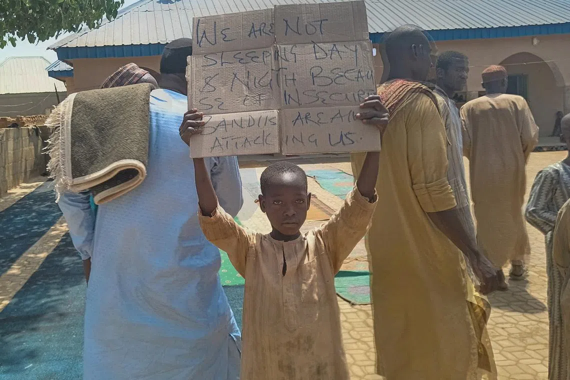FILE PHOTO: A boy holds a sign to protest against, what a teacher, local councilor and parents said, the kidnapping of hundreds school pupils by gunmen after the Friday prayer in Kaduna, Nigeria March 8, 2024. REUTERS/Stringer/File Photo