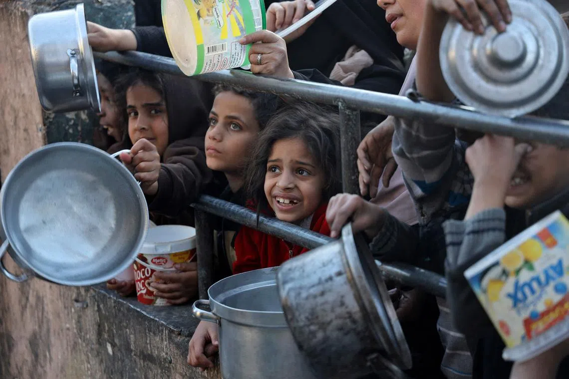 Displaced Palestinians collecting food donated by a charity before an iftar meal, the breaking of the fast, on the first day of the Muslim holy fasting month of Ramadan in Rafah, on the southern Gaza Strip on Mar 11, 2024.