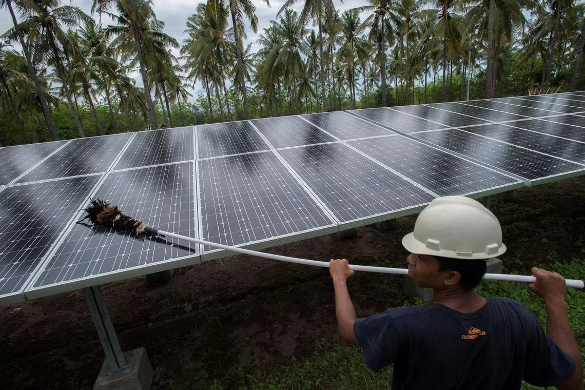 FILE PHOTO: An employee of PT Perusahaan Listrik Negara (PLN) cleans the surface of solar panels at a solar power generation plant in Gili Meno island, in this December 9, 2014 photo taken by Antara Foto. REUTERS/Antara Foto/Widodo S. Jusuf./File Photo ATTENTION EDITORS - FOR EDITORIAL USE ONLY. THIS IMAGE HAS BEEN SUPPLIED BY A THIRD PARTY. MANDATORY CREDIT. INDONESIA OUT./File Photo