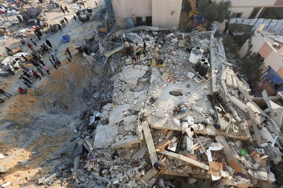 FILE PHOTO: Palestinians gather at the site of an overnight Israeli air strike on a house, in Khan Younis in the southern Gaza Strip, July 28, 2025. REUTERS/Ramadan Abed/File Photo