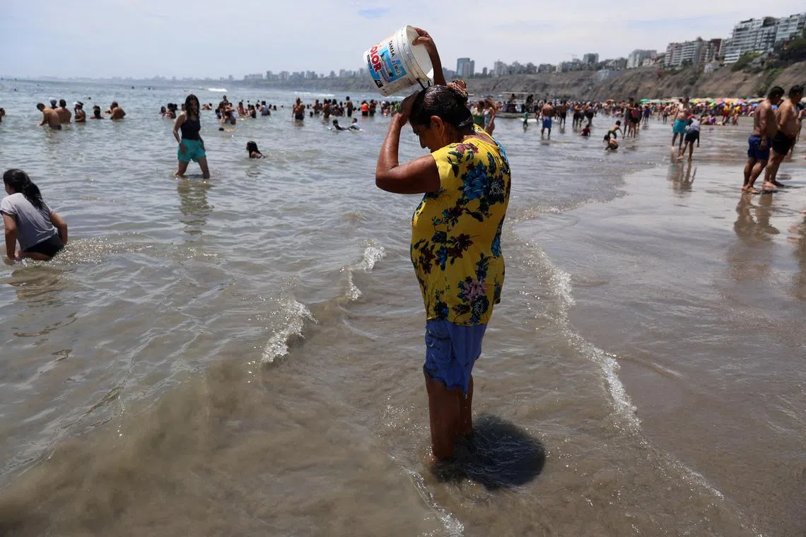 FILE PHOTO: A woman pours water on her head as bathers enjoy a summer day due to the high temperatures at Agua Dulce beach in the Chorrillos district in Lima, Peru, February 25, 2024. REUTERS/Sebastian Castaneda/File Photo