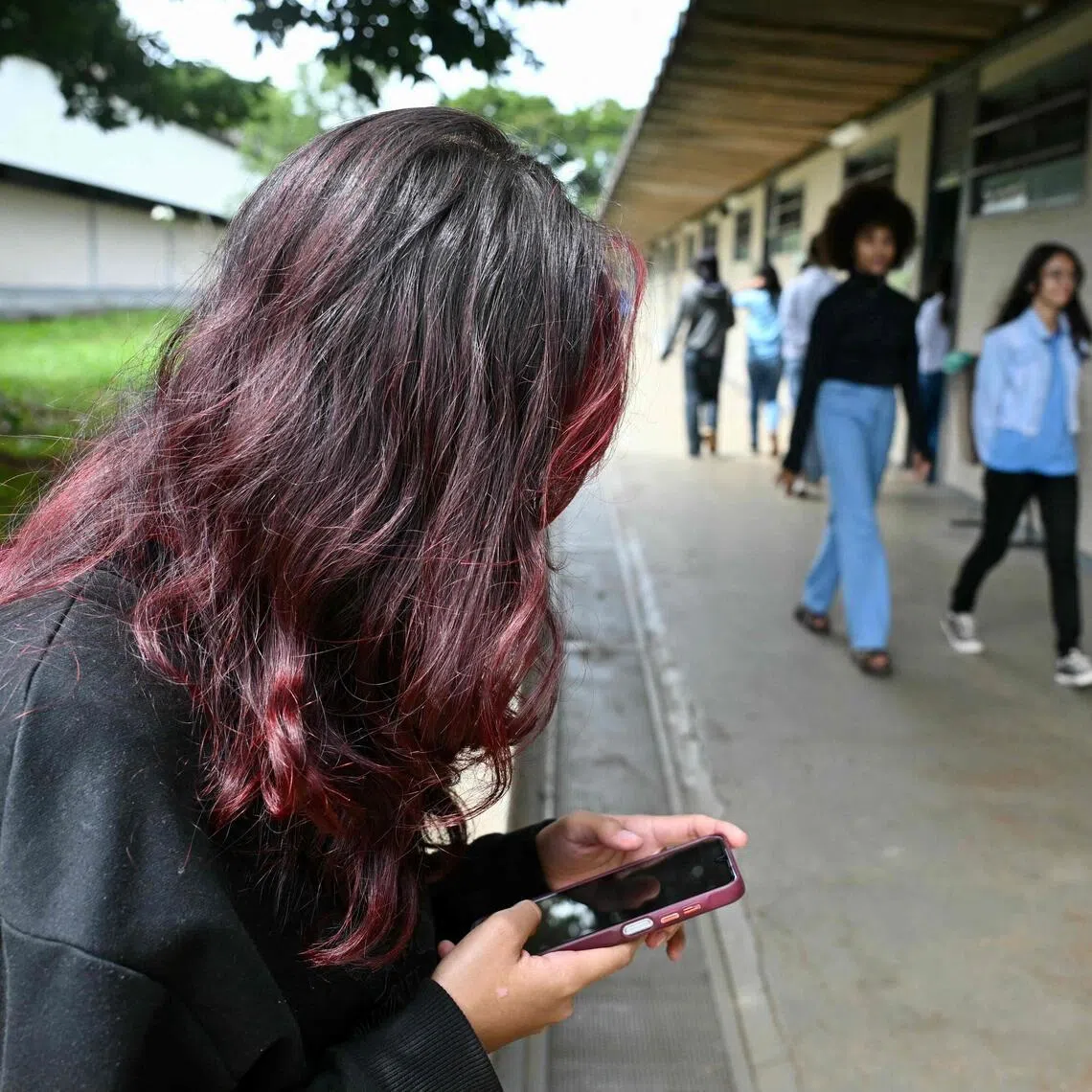 A young student uses her mobile phone at a public school in Planaltina, Brasilia, on March 16.