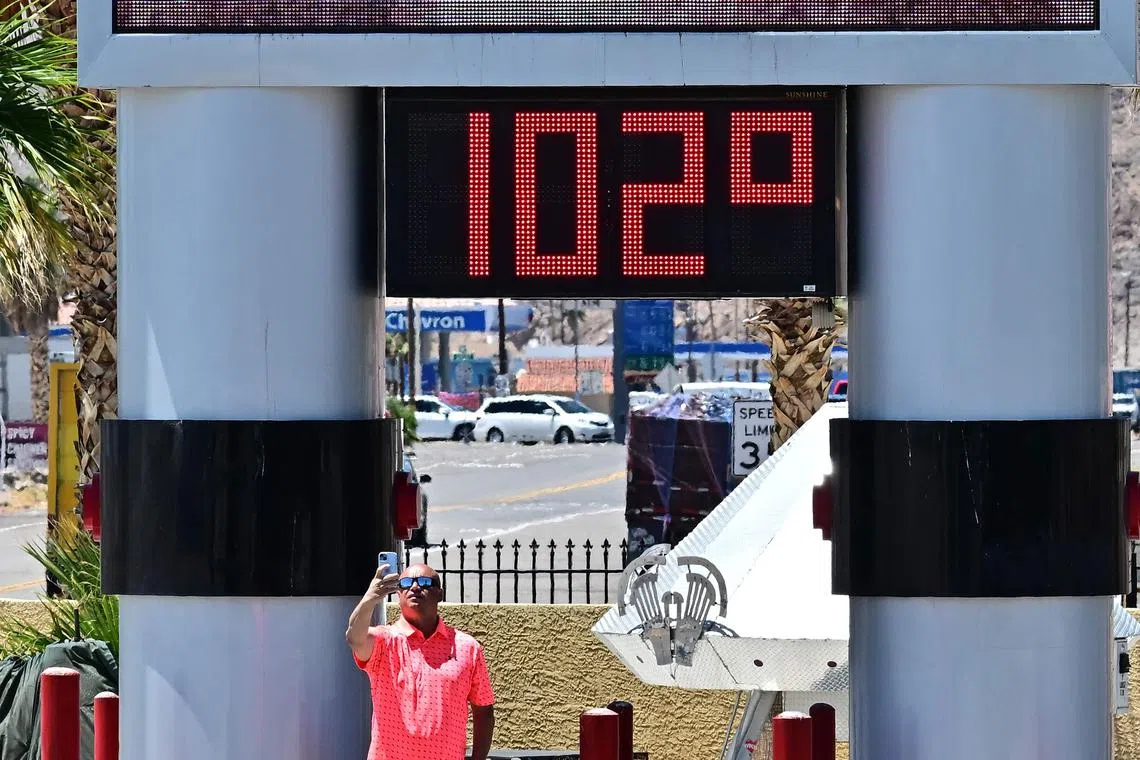 A man takes a selfie beside a thermometer showing 102 degrees farenheit (38.8 deg C) in Baker, California on Tuesday. 