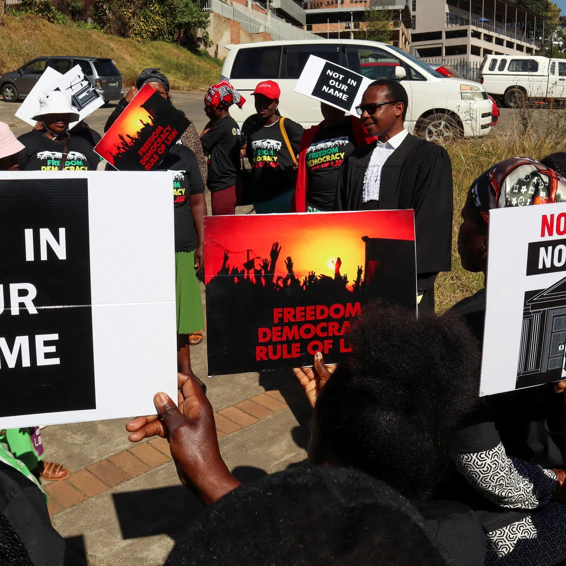 Protesters hold placards as lead applicant and lawyer Mzwandile Masuku addresses them outside the court in Mbabane, Eswatini, August 22, 2025. Activists are challenging a secretive agreement with former U.S. President Donald Trump's administration to accept third-country deportees, which they argue is unconstitutional. REUTERS/Zakhele Mabuza