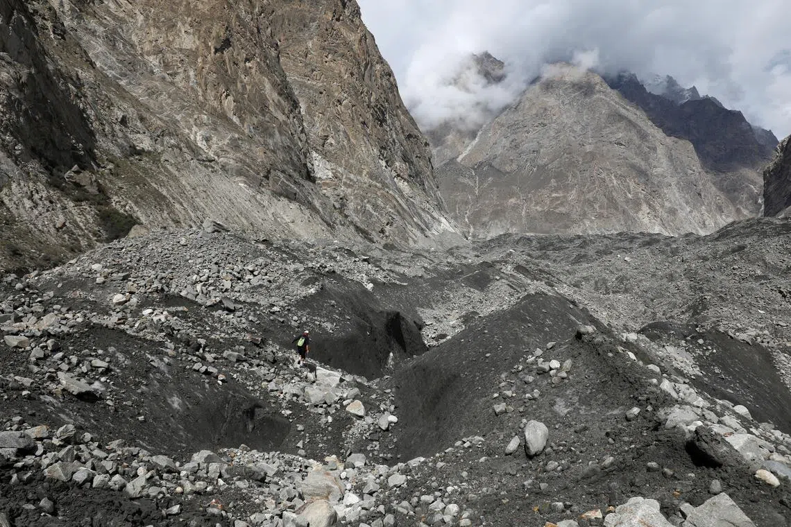 Tariq Jamil, 51, chairman of the Community Based Disaster Risk Management Centre, walking with a hiking stick to check the ice on the Shisper glacier, near Hassanabad village, Hunza valley, in the Karakoram mountain range in the Gilgit-Baltistan region of Pakistan, Oct 10, 2023. On the steep slope of a glacier jutting through the Hunza valley in Pakistan's mountainous far north, Tariq Jamil measures the ice's movement and snaps photos. Later, he creates a report that includes data from sensors and another camera installed near the Shisper glacier to update his village an hour's hike downstream. 