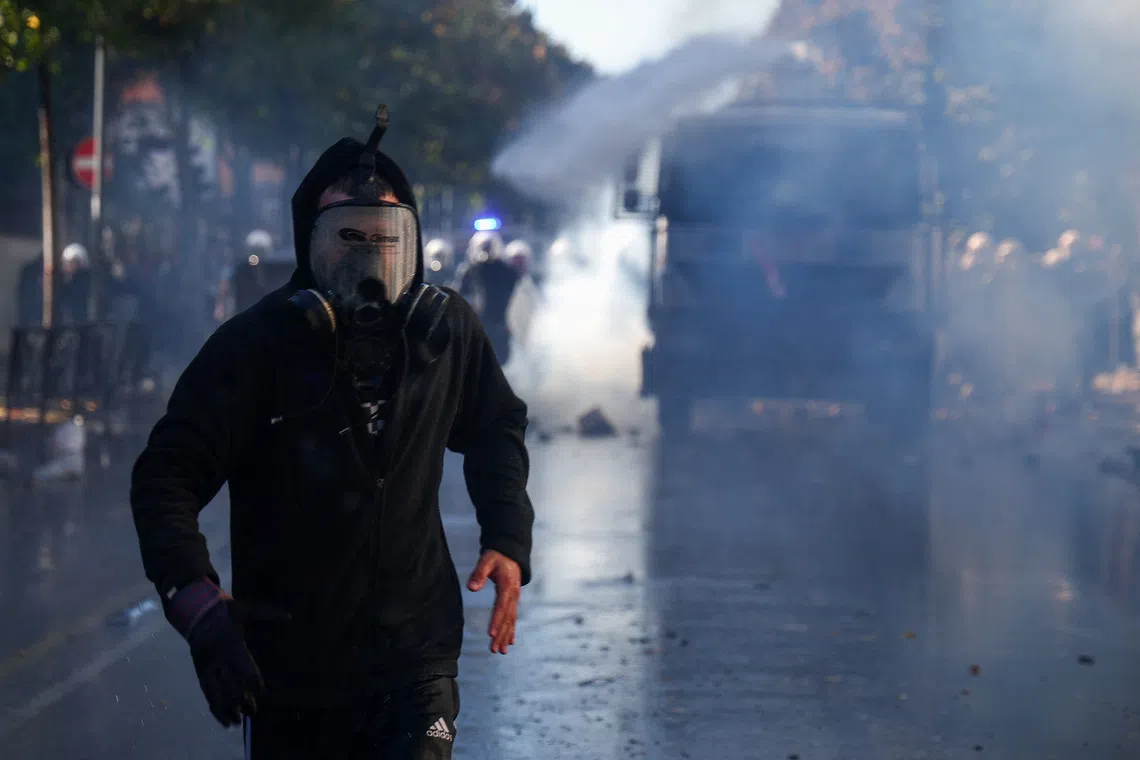 A demonstrator wearing a protective mask runs ahead of a water cannon truck during an anti-government protest by students in Tirana, Albania, October 16, 2026. REUTERS/Florion Goga