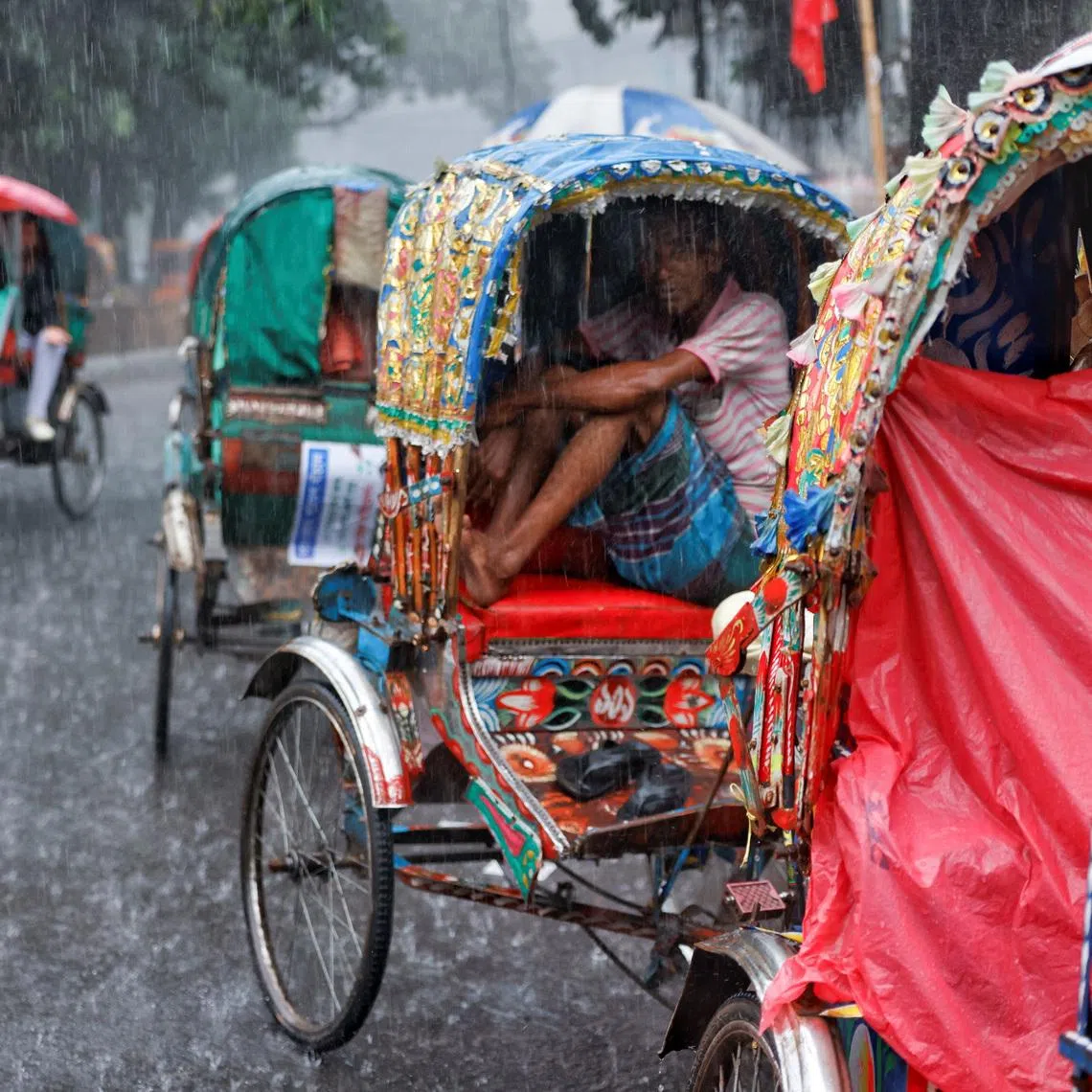 Rickshaw drivers sitting inside their rickshaws to take cover during torrential rain in Dhaka, Bangladesh, on July 7.
