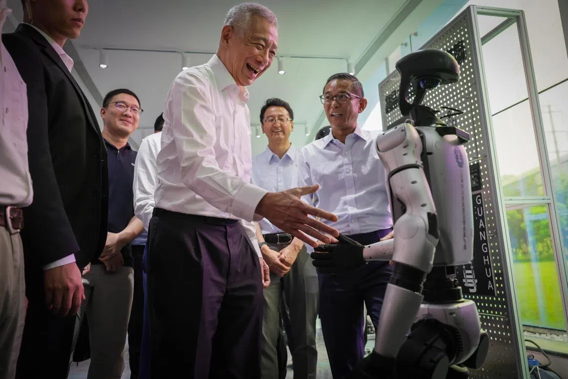 Senior Minister Lee Hsien Loong shaking hand with a robot when he toured the Shanghai Municipal Humanoid Robot Innovation Incubator on May 21.