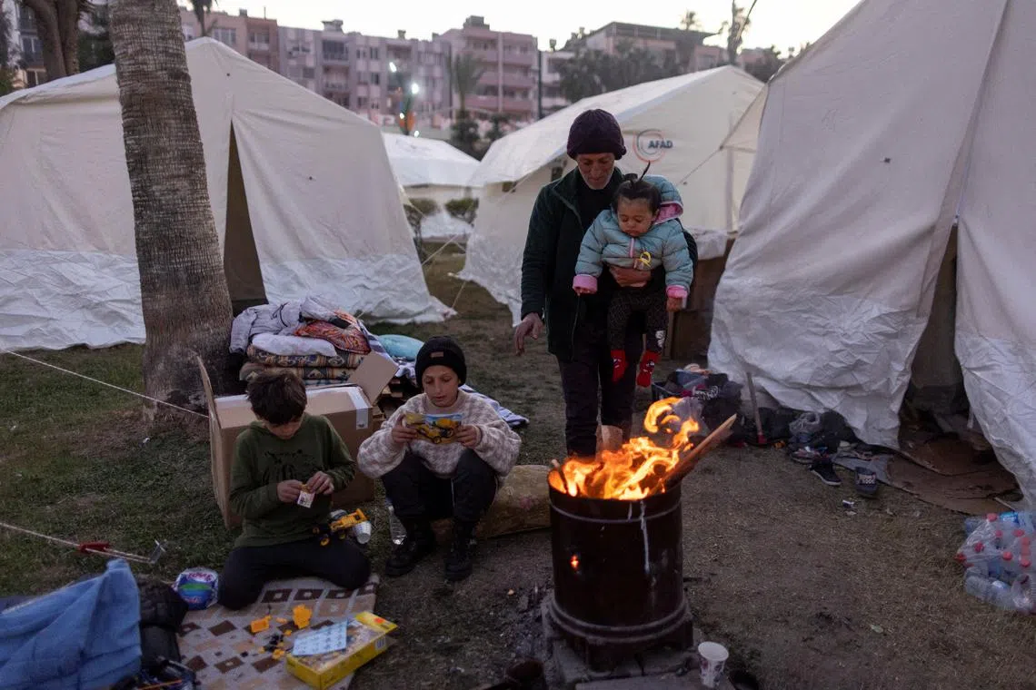 A Syrian family gathering around a fire for warmth, at a camp for displaced people in Iskenderun city, Hatay province, Turkey, on Feb 14, 2023. 