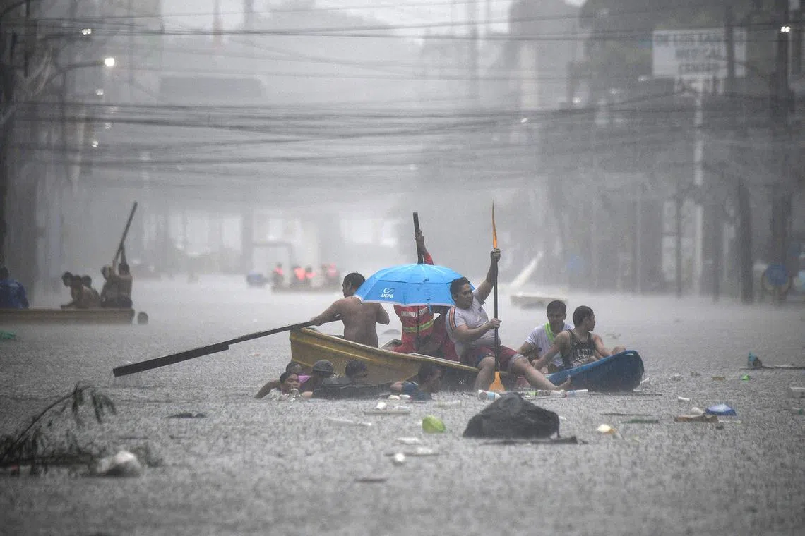 Rescuers paddling their boats along a flooded street in Manila on July 24, 2024, amid heavy rains brought by Typhoon Gaemi. 