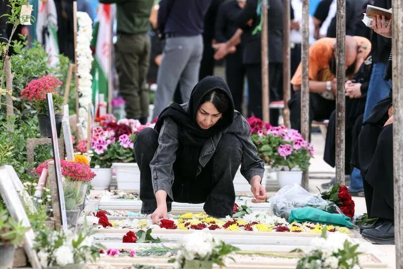 An Iranian woman adorning the grave of a loved one killed during the US-Israeli war against the Islamic republic in southern Tehran on April 23, 2026.