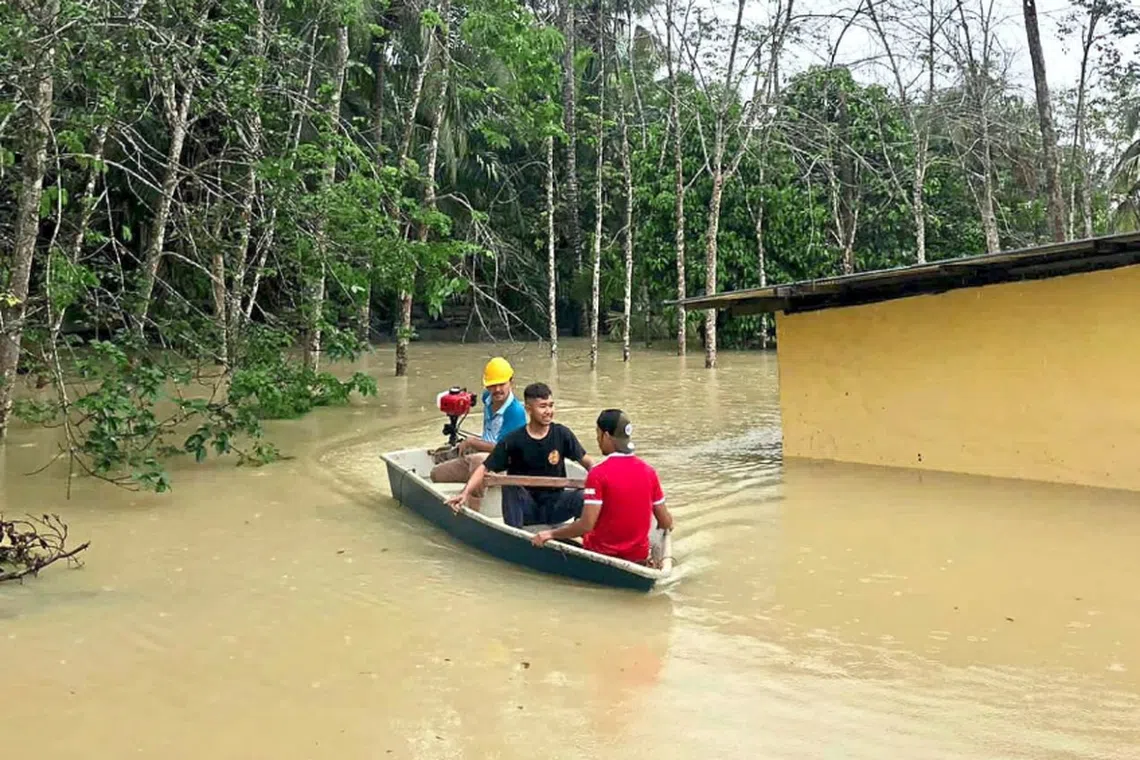 Mr Ahmad Asjam (in blue) helping to evacuate his neighbours after their village in Kota Tinggi was flooded.
