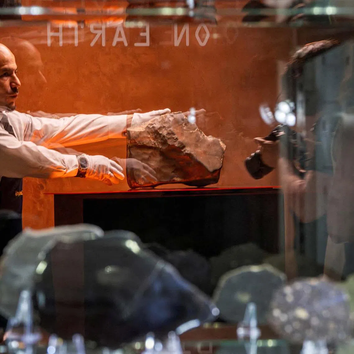 A handler is reflected on a showcase as he organizes meteorite NWA 16788, the largest known piece of Mars on Earth, during the press preview of Sotheby’s Natural History auction in New York City on July 8. 