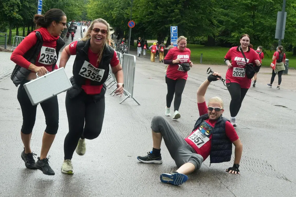 Participants of a fun run around locations in the video for the track Sandstorm by Finnish electronic music artist and producer Darude reenact a scene from the video as they near the finish line in Helsinki, Finland on Aug 31, 2025.
