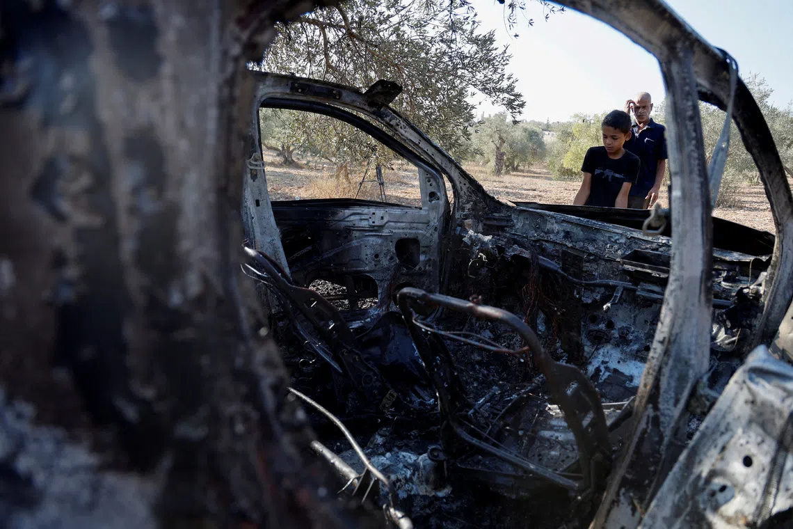People inspect a burnt vehicle at the site where Israeli forces killed three Palestinians, near Jenin, in the Israeli occupied West Bank October 28, 2025. REUTERS/Raneen Sawafta