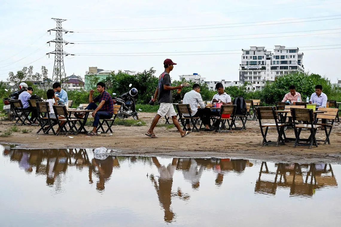 TOPSHOT - People sit together at a makeshift outdoor dining area in Phnom Penh on October 19, 2023. (Photo by TANG CHHIN Sothy / AFP)
