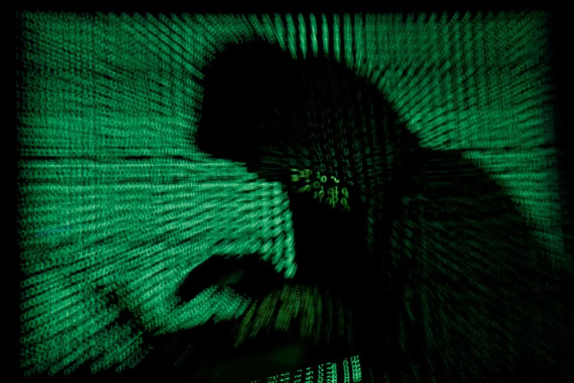 FILE PHOTO: A hooded man holds a laptop computer as cyber code is projected on him in this illustration picture taken on May 13, 2017.  