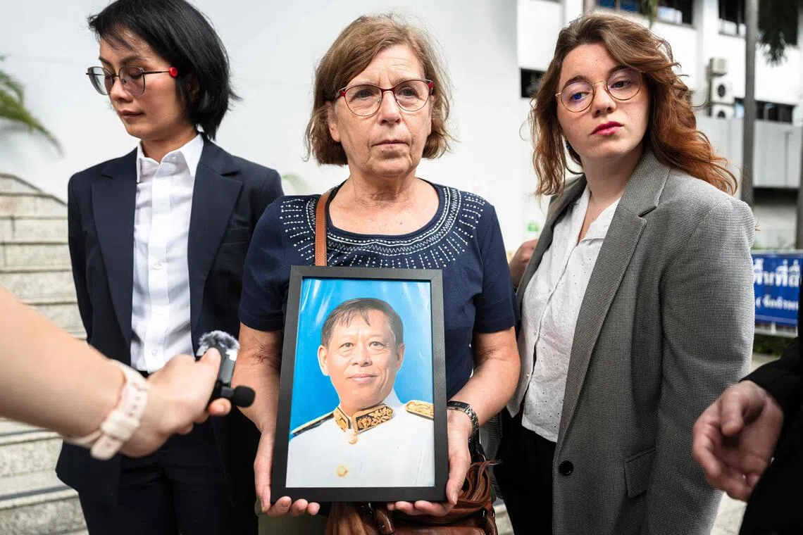 TOPSHOT - Anne-Marie Lim (C), widow of former Cambodian opposition lawmaker Lim Kimya who was shot dead in Bangkok, holds a picture of her late husband as she speaks to the press before the first witness hearing in the trial at the Criminal Court in Bangkok on September 30, 2025. The trial of the alleged killer of a Cambodian opposition politician in Bangkok began on September 30, with his widow calling for justice and to "know the mastermind" behind the murder. (Photo by Chanakarn Laosarakham / AFP)
