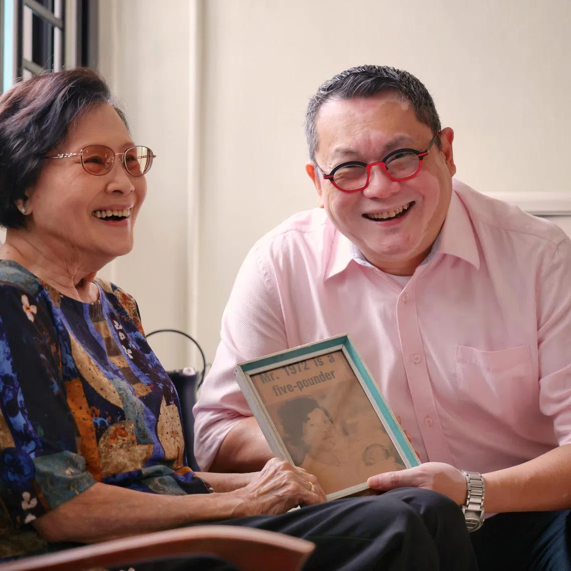 Mr Daniel Cheong, the first baby born in Singapore in 1972, and his mother, Madam Lee, with a framed clipping of The Straits Times talking about his birth.