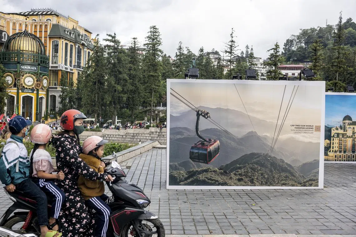  A family rides past a collection of Sun Group posters in central Sapa, Vietnam promoting the Fansipan Legend Cable Car line, which holds a Guinness World Record, on July 1, 2023. The country is in the middle of a cable-car bonanza, much of it driven by the over-the-top developments of the Sun Group, which feature giant Buddhas, ersatz European enclaves and selfie spots galore. (Justin Mott/The New York Times)