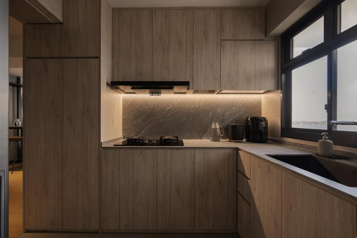 Under-cabinet lighting highlights the veining of the stone backsplash, giving the kitchen a calm, refined glow.