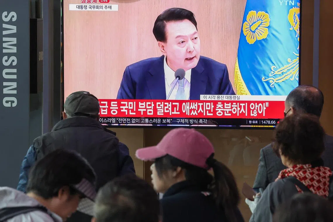 People watch a broadcast of South Korean President Yoon Suk Yeol's remarks at Seoul Station on April 16, 2024.