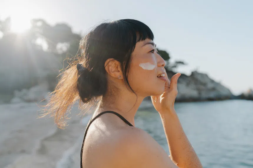 Best Japanese sunscreen: Chinese woman applying sunscreen outdoors in the sun