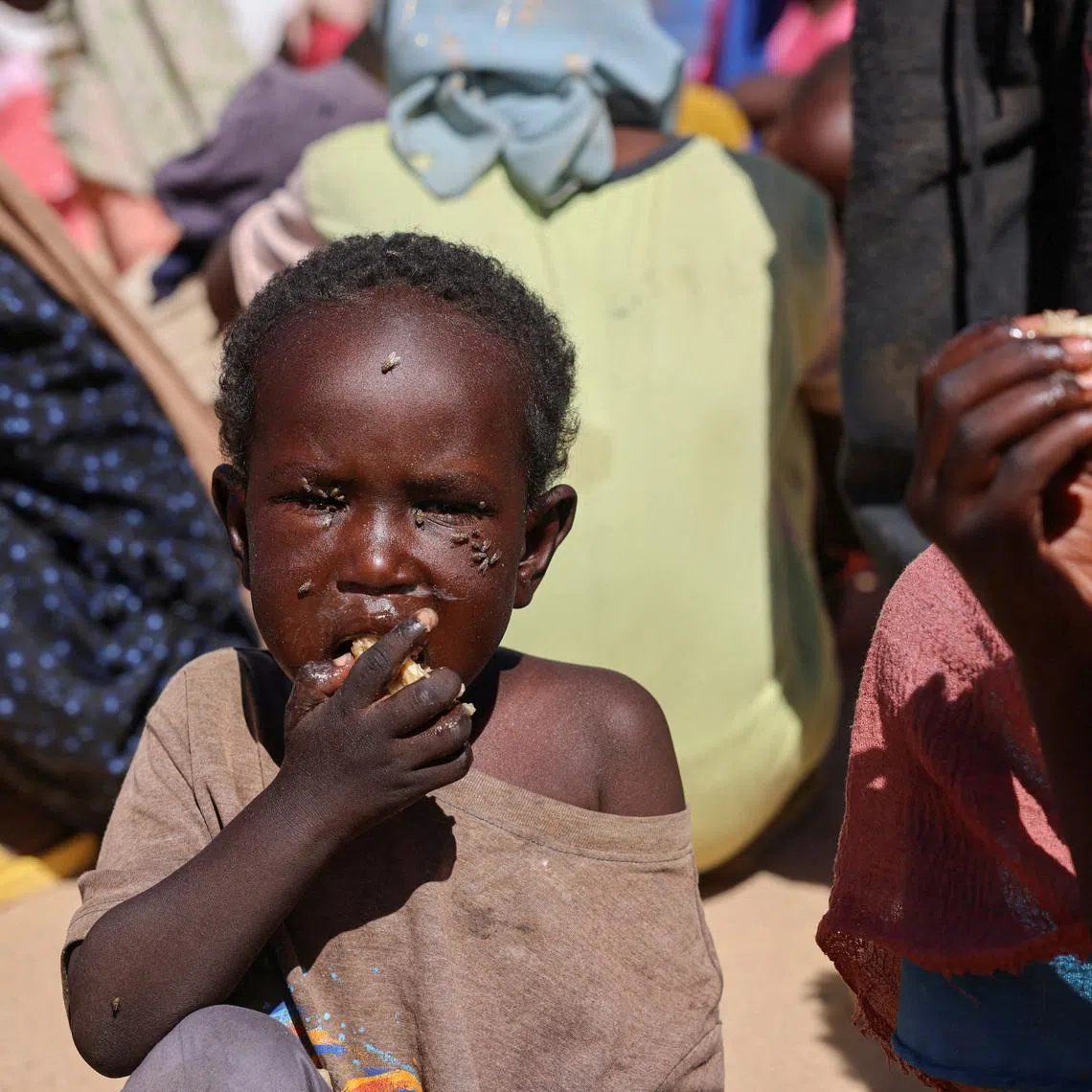 FILE PHOTO: A Sudanese refugee child from Al-Fashir eats a shared a meal at the Tine transit refugee camp, amid the conflict between the paramilitary Rapid Support Forces (RSF) and the Sudanese army, in eastern Chad, November 22, 2025. REUTERS/Amr Abdallah Dalsh/File Photo